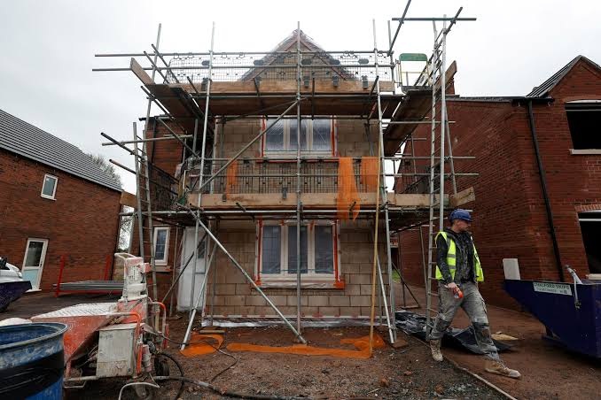 Domestic house under construction with scaffolding, blockwork and site worker